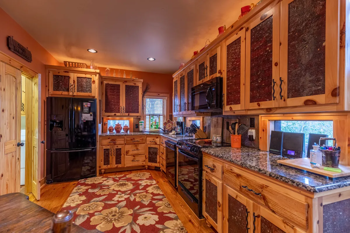 A kitchen scene featuring custom wooden cabinetry, gleaming granite countertops, a decorative rug, and modern appliances. The layout is open and inviting, ideal for preparing meals and enjoying communal time with loved ones.